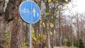 Pedestrian and bicycle road sign with white blue markings on a background of trees and blue sky in a park in autumn. Separate Royalty Free Stock Photo