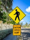 Pedestrian and caution speed bump sign in a tropical setting.