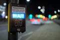 Pedestrian crossing button and illuminated wait sign with out of focus traffic in the background Royalty Free Stock Photo