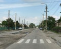 pedestrian crossing of the city street with poor road, old tram tracks, pillars and single-storey private houses Royalty Free Stock Photo