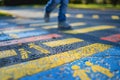 Pedestrian crossing painted with blue and yellow colors and human figures, close-up of the textured road surface