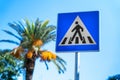 Pedestrian crossing road sign on blue background at resort against palm tree sky Royalty Free Stock Photo