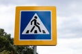 Pedestrian crossing road sign in yellow frame on gray sky, symbol of crosswalk on street Royalty Free Stock Photo