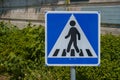 Pedestrian crossing sign with green bushes and a concrete wall in the background Royalty Free Stock Photo