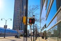 A pedestrian crossing signal with a red hand and a number three attached to a black pole with bare winter trees