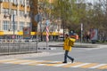 Pedestrian crossing Yandex courier, food in yellow uniform with thermo bag on back, food delivery in self-isolation conditions