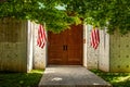 Pedestrian entrance to contemporary estate with industrial looking concrete walls with American flags hanging to each side-shaded
