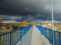 A pedestrian footbridge over the tracks on an autumn day, with a spectacularly cloudy sky above. Royalty Free Stock Photo