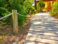 Pedestrian path made with wooden planks on the floor and handrail posts and rope that reach a wooden house Royalty Free Stock Photo