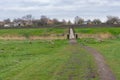 Pedestrian path through spring meadow to old foot-bridge Royalty Free Stock Photo