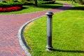 A pedestrian pavement with red tiles stretches along a curved path.