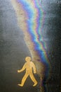 Pedestrian pavement sign with oil and water rainbow effect on asphalt. Eco oil concept. Royalty Free Stock Photo