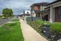 Pedestrian sidewalk in a new suburban neighbourhood along with a row of modern residential houses Royalty Free Stock Photo