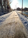 Pedestrian sidewalk on the side of a road cleared from snow and sprinkled with sand and salt