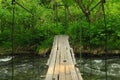 Pedestrian suspended wooden bridge over mountain river