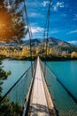 Pedestrian suspended wooden bridge over mountain river. Long bridge across the river against background of mountains Royalty Free Stock Photo