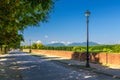 Pedestrian walking path street with lamps on defensive city wall in clear sunny day with Tuscany hills and mountains and clear blu
