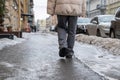 Person walking on slippery sidewalk rear view. Pavement covered with slippery ice. Frozen rain.