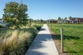 A pedestrian walkway/footpath leads to a residential neighbourhood with some modern Australian homes. Suburban view over a park