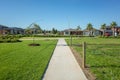 A pedestrian walkway/footpath leads to a residential neighbourhood with some modern Australian homes. Suburban view over a park