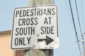pedestrians cross at south side only writing caption text square sign with arrow. p