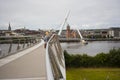 Pedestrians crossing the Derry Peace Bridge towards the walled city