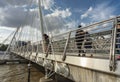 Pedestrians crossing The Queen`s Golden Jubilee Footbridges in the summertime Royalty Free Stock Photo