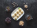 Pedha Indian sweet, Milk Fudge with tea cups and dates in a black background. Top view