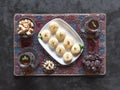 Pedha Indian sweet, Milk Fudge with tea cups and dates in a black background. Top view