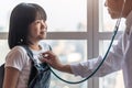 Pediatric care with happy child patient and pediatrician doctor examining girl kid heart health with stethoscope Royalty Free Stock Photo