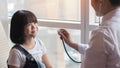 Pediatric care with happy child patient and pediatrician doctor examining girl kid heart health with stethoscope Royalty Free Stock Photo