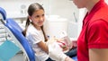 Female pediatric dentist educating girl about proper tooth cleaning