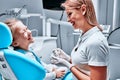 Pediatric dentist educating a smiling little girl about proper tooth-brushing, demonstrating on a model