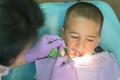 Pediatric dentist examining a little boys teeth in the dentists chair at the dental clinic. A child with a dentist in a dental Royalty Free Stock Photo