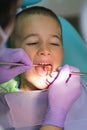 Pediatric dentist examining a little boys teeth in the dentists chair at the dental clinic. Close up of dentist examination little Royalty Free Stock Photo