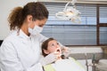 Pediatric dentist examining a little girls teeth in the dentists chair