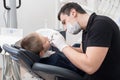 Pediatric dentist examining teeth of boy patient in dental clinic using dental tools - probe and mirror Royalty Free Stock Photo