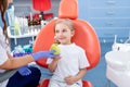 Pediatric dentist gives a little girl a big green apple. beautiful girl is smiling in dentist`s office. concept is a children`s Royalty Free Stock Photo