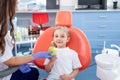 Pediatric dentist gives a little girl a big green apple. beautiful girl is smiling in dentist`s office. concept is a children`s Royalty Free Stock Photo