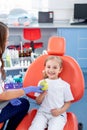 Pediatric dentist gives a little girl a big green apple. beautiful girl is smiling in dentist`s office. concept is a children`s Royalty Free Stock Photo