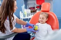 Pediatric dentist gives a little girl a big green apple. beautiful girl is smiling in dentist`s office. concept is a children`s Royalty Free Stock Photo