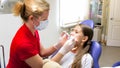 Female pediatric dentist inspecting girls teeth with instruments