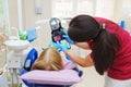 A pediatric dentist shows a small patient a photo of teeth on a camera screen.