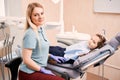 Pediatric dentist sitting beside adorable little girl in dental office.