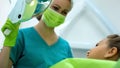 Pediatric dentist smiling to teenage girl, brave patient waiting for procedure Royalty Free Stock Photo