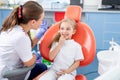 Pediatric dentist talks to a little girl and tells her how to take care of her teeth. beautiful girl is smiling in dentist`s Royalty Free Stock Photo