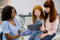 Pediatric and famile dentistry, orthodontics. Professional black woman dentist showing tablet pc computer to kid girl