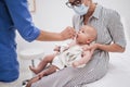 Pediatrician administring oral vaccination against rotavirus infection to little baby in presence of his mother