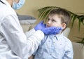 Pediatrician checking sore throat of baby boy at home