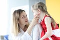 Pediatrician doctor examines little girl throat closeup